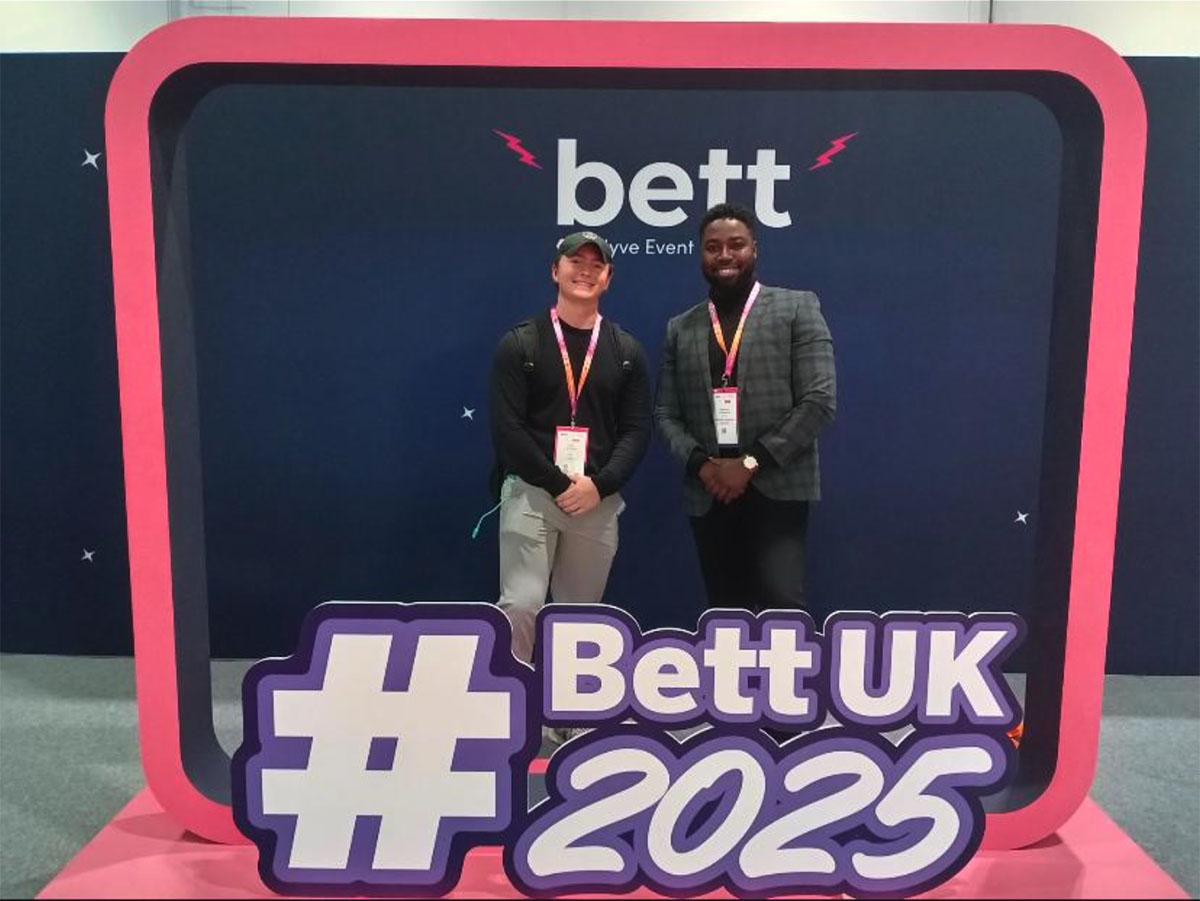 2 people standing behind BETT display