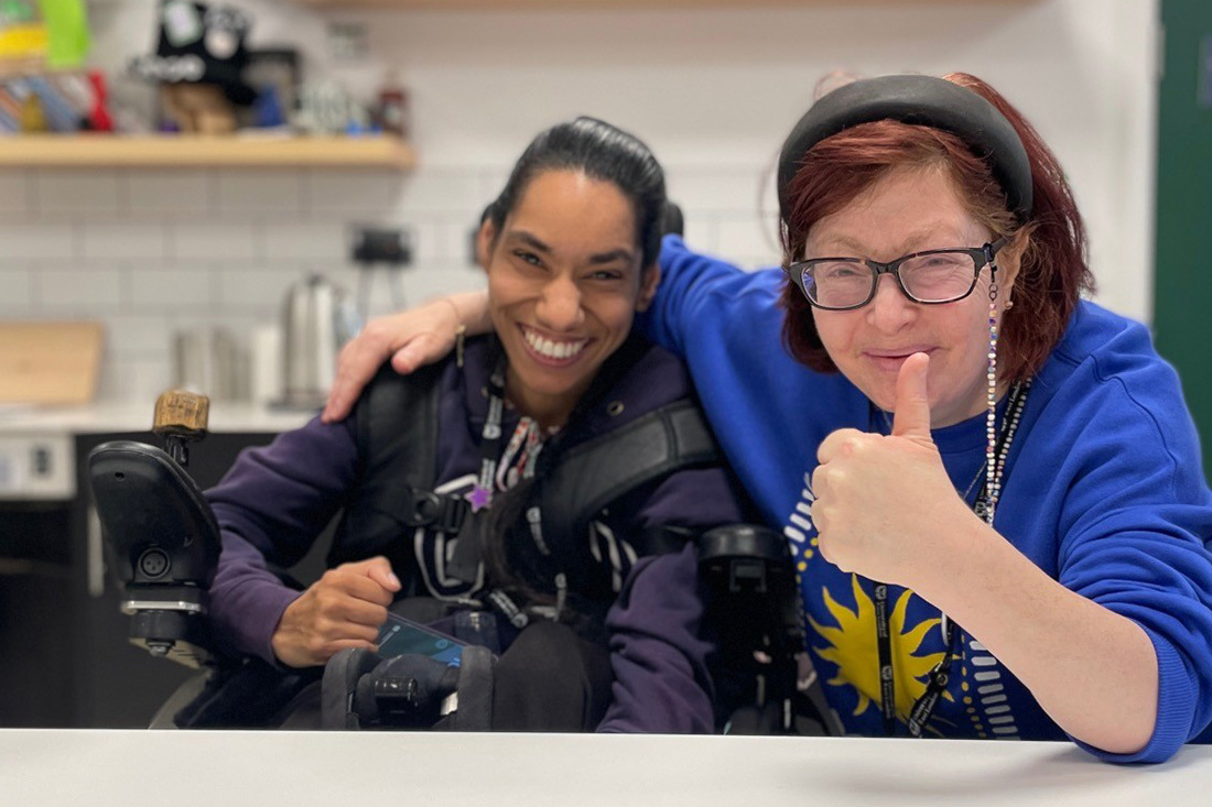 two women smiling and giving thumbs up