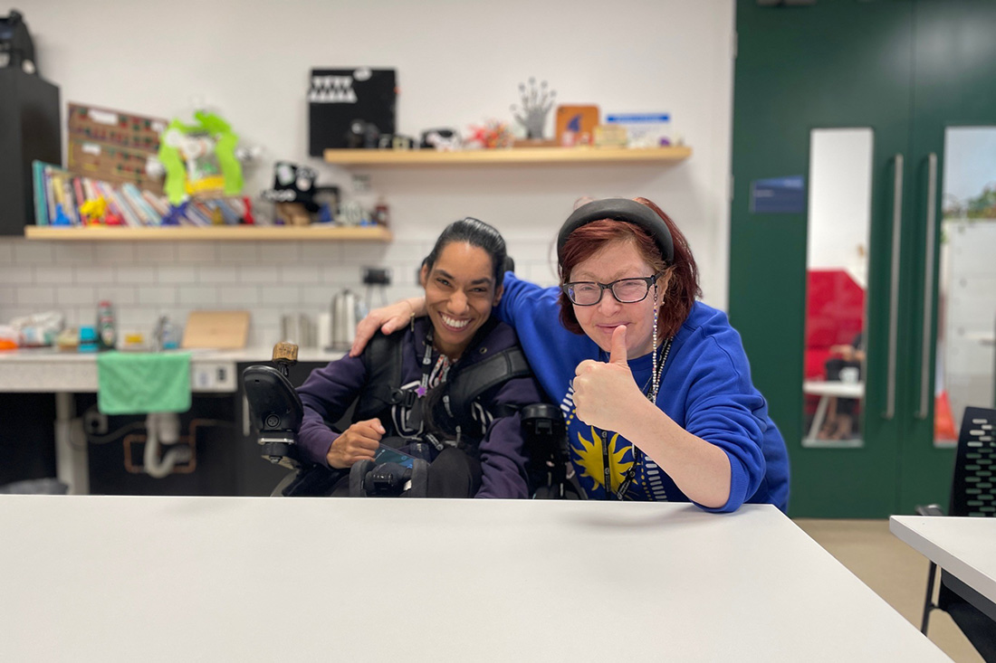 two women smiling and giving thumbs up