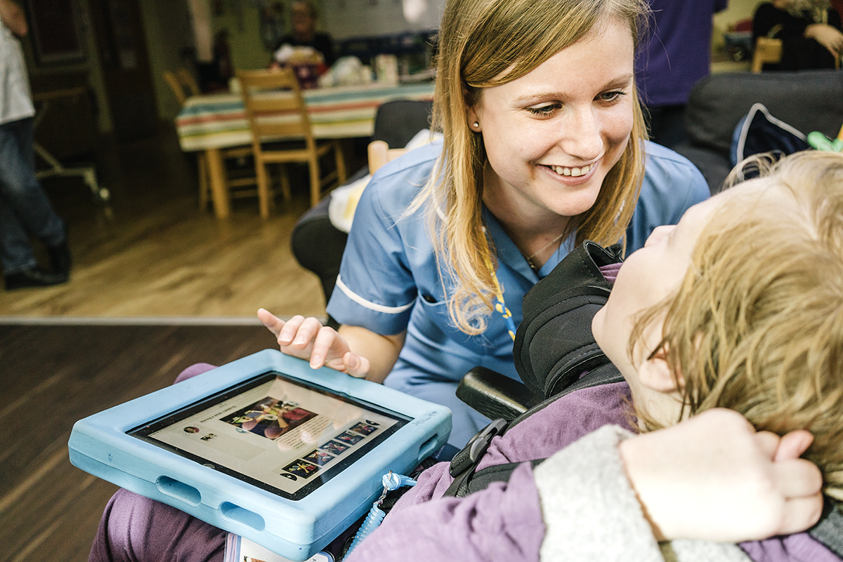 Young person in wheelchair shows Wiki to supporter