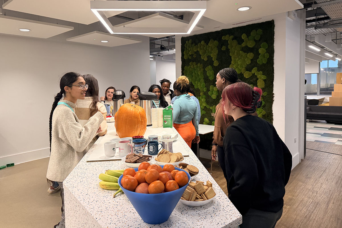 people around a table of food with a pumpkin in the middle of the table