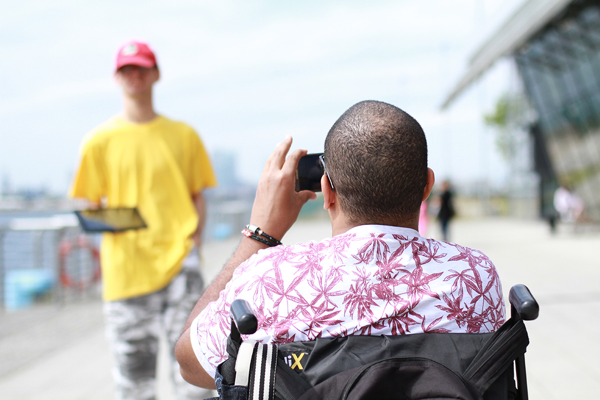 Young person in wheelchair takes photo of friend