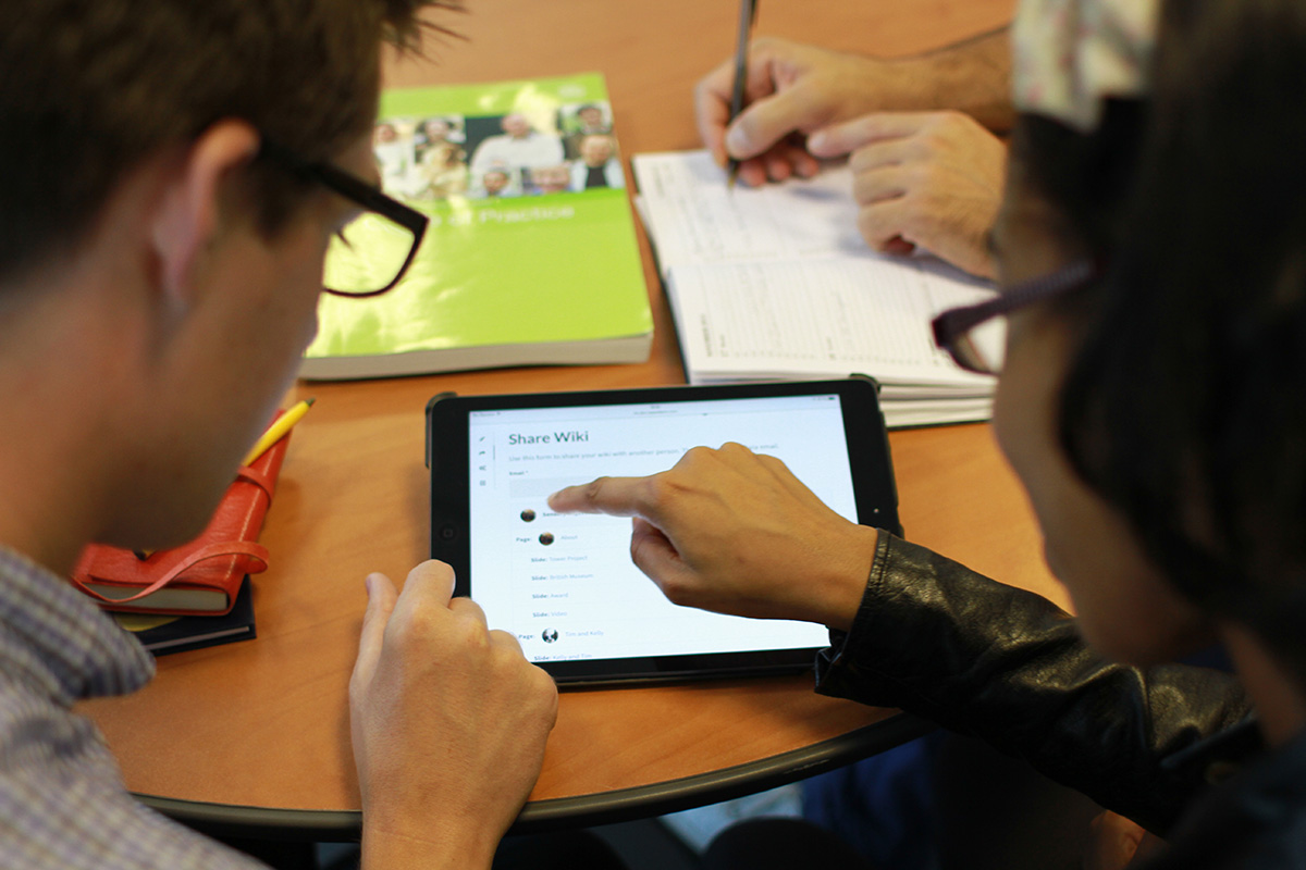 Two people at a table looking at a Wiki on a tablet