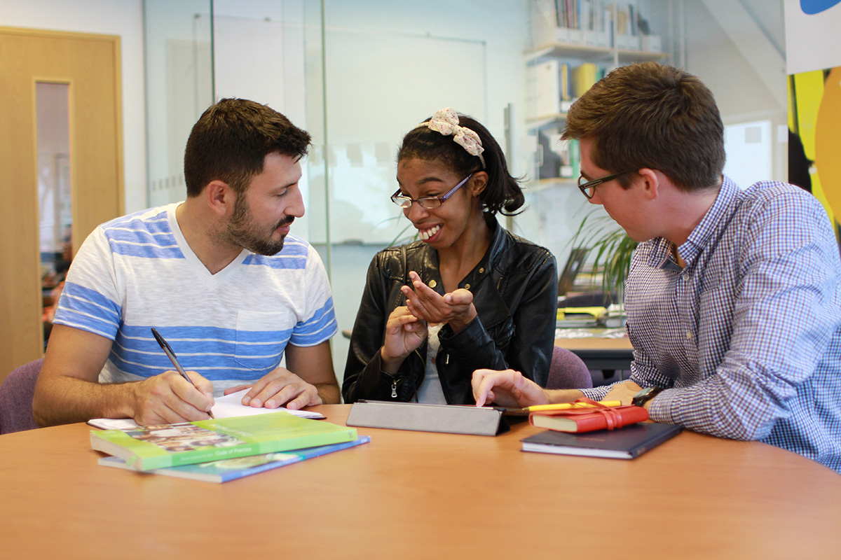 Two supporters planning at table with young person